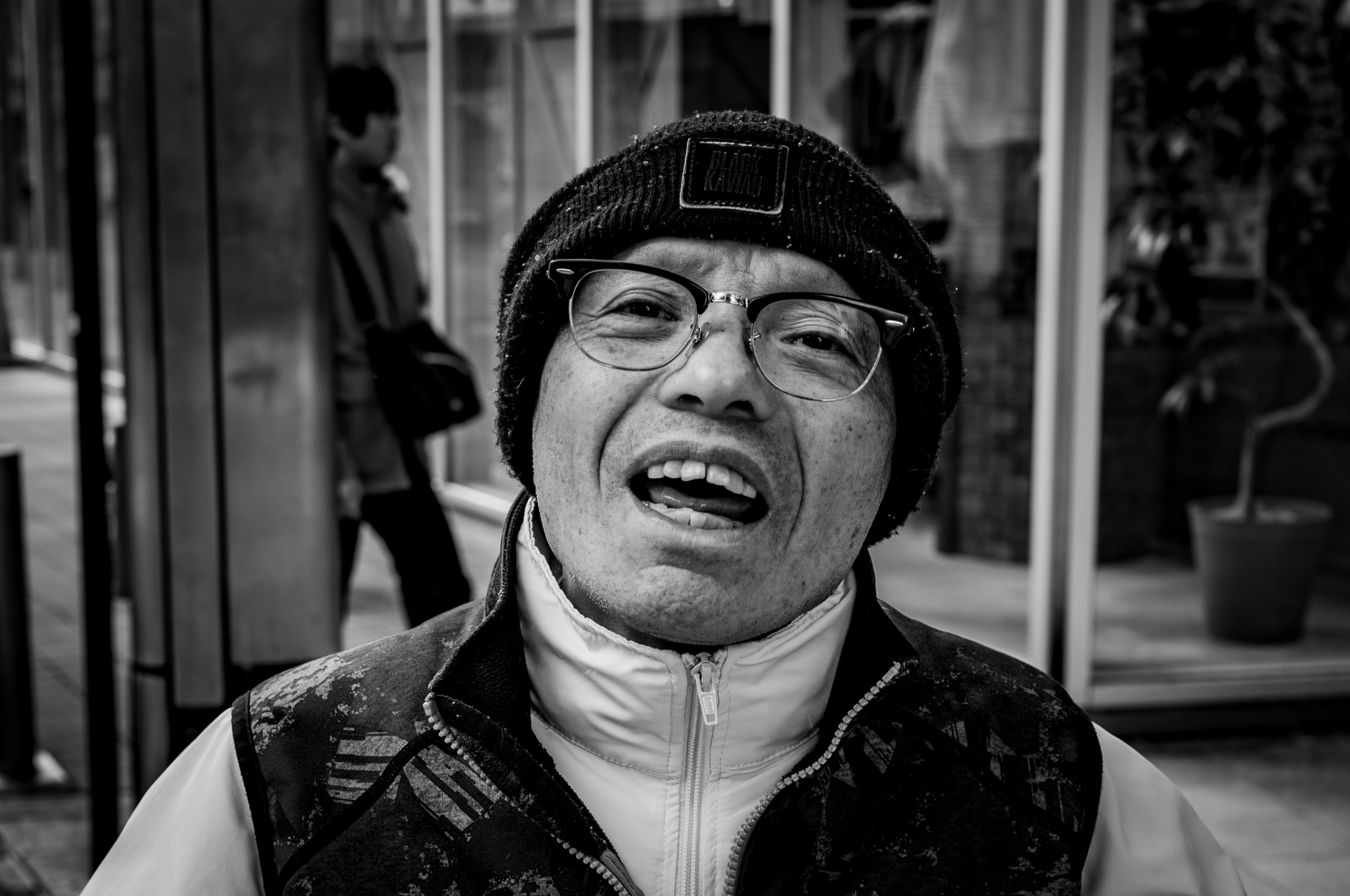 He opens his mouth as if the street owes him an answer.