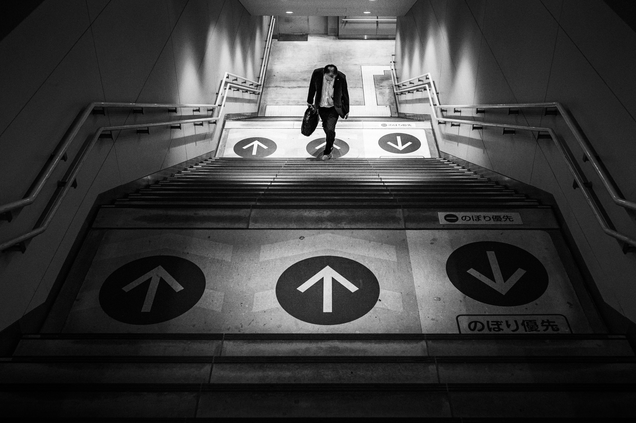 A man descends a stairway between painted arrows pointing up and down.
